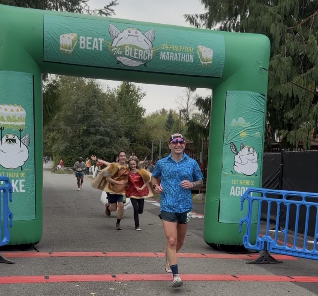Jason Bahamundi smiling as he crosses the finish line at the Beat The Blerch Half Marathon after running 1:59:23, fifteen years after his 1:36:29 half-marathon PR.